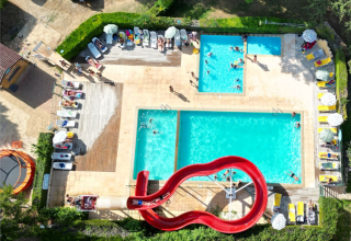 Aerial view of pool with red slide and sun loungers at Camping Le Céou, Nouvelle-Aquitaine, France.