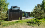 Cabaña de madera negra en un entorno verde en el parque vacacional De Klepperstee, Kleproos, Países Bajos.