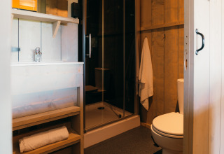 Baño en la tienda Safari cottage en Holiday Park Sallandshoeve, Países Bajos, con ducha y aseo.