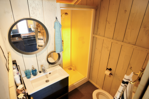 Baño con ducha, espejos y lavabo en una Safaricottage XL en Holiday Park Sallandshoeve, Países Bajos.