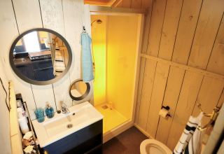 Salle de bain avec douche, miroir et lavabo dans une Safaricottage XL au Holiday Park Sallandshoeve, Pays-Bas.