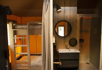 Interno di una tenda safari di lusso con letti a castello, bagno e doccia al Holiday Park Sallandshoeve.