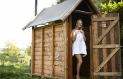 Woman in towel standing in outdoor shower hut next to safari tent with private hot shower facility.