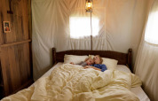 A mother and child peacefully sleeping in a cozy bed inside a comfortable safari tent bedroom.