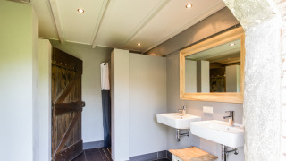 Modernes Badezimmer im Safarizelt mit zwei Waschbecken, Holzdetails und großer Spiegel am Bauernhaus.