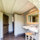 Modern badkamer in safaritent met dubbele wastafels, grote spiegel en rustieke houten accenten bij boerderij.