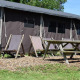 Area esterna con sedie a sdraio e tavolo da picnic davanti a tenda safari con doccia privata in fattoria.
