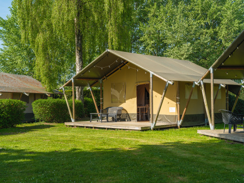 Tenda safari a De Scherpenhof nei Paesi Bassi con terrazza moderna e prato verde circostante.