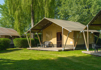 Safaritent bij De Scherpenhof in Nederland met terras, zitmeubilair en groene omgeving.