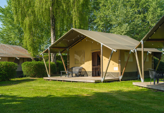 Safari-Zelt auf De Scherpenhof in den Niederlanden mit Terrasse, Bänken und grüner Umgebung.