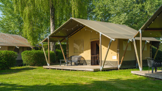 Safari tent at De Scherpenhof in the Netherlands with modern terrace seating and lush green grass.
