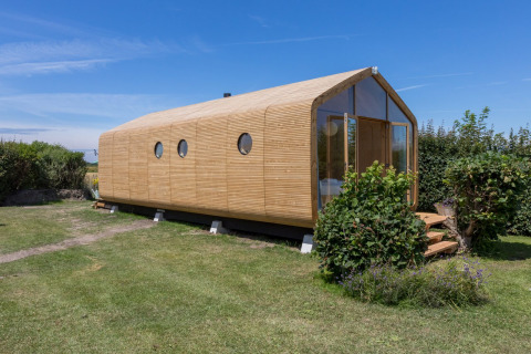 Cabaña moderna de madera en Welcome In - Zeeland, parque vacacional en Zelanda, Países Bajos, rodeada de césped.