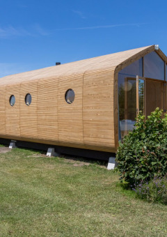 Cabaña moderna de madera en Welcome In - Zeeland, parque vacacional en Zelanda, Países Bajos, rodeada de césped.