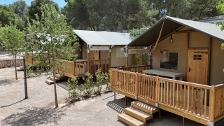 Tienda safari Outback en el camping Vilanova Park en España, rodeada de árboles y naturaleza.
