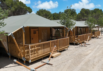 Safari-telte med træverandaer på Vilanova Park campingplads i Spanien under en solrig himmel.