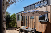 Udendørs spiseplads med parasol ved det lille hus Tiny Home Arrozal ved TAIGA Delta de l'Ebre i Spanien.