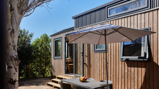 Außenbereich mit Tisch und Sonnenschirm vor dem Tiny Home Arrozal bei TAIGA Delta de l'Ebre in Spanien.