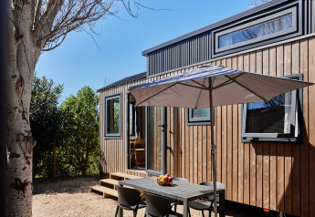 Zona de comedor exterior con mesa y sombrilla en Tiny Home Arrozal, TAIGA Delta de l'Ebre, España.