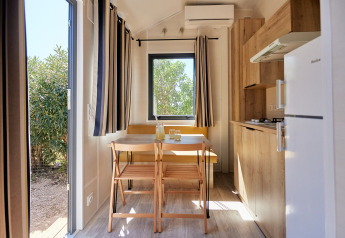 Interno luminoso e moderno del Tiny Home Arrozal al TAIGA Delta de l'Ebre, Spagna, con cucina e zona pranzo.
