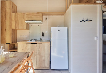 Petite cuisine moderne au Tiny Home Arrozal, TAIGA Delta de l'Ebre, Espagne, avec meubles bois et réfrigérateur blanc.