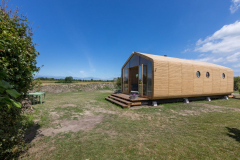 Modern tiny house met houten gevel in een open veld bij Welcome In - Zeeland, vakantiepark in Zeeland, Nederland.