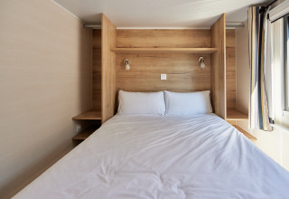 Kleines Schlafzimmer mit Doppelbett, Holzwänden und großen Fenstern in Tiny Home Arrozal, TAIGA Delta de l'Ebre.