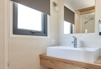 Salle de bain moderne dans Tiny Home Arrozal à TAIGA Delta de l'Ebre, Espagne, avec lavabo, miroir et fenêtre.