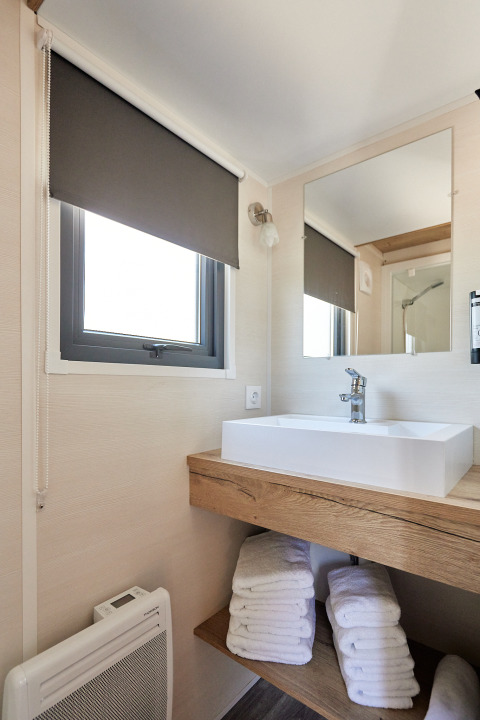 Moderne badkamer in Tiny Home Arrozal bij TAIGA Delta de l'Ebre, Spanje, met wastafel, spiegel en venster.