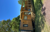 Cabaña Prestige Cottage en Camping Seasonova Les Marguerites, Francia, rodeada de césped y cielo azul.