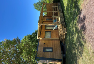 Cabaña Prestige Cottage en Camping Seasonova Les Marguerites, Francia, rodeada de césped y cielo azul.