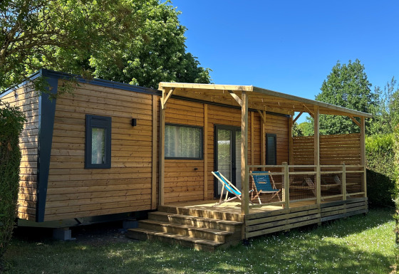 Lodge Prestige Cottage al Camping Seasonova Les Marguerites in Francia, circondato dal verde e cielo sereno.