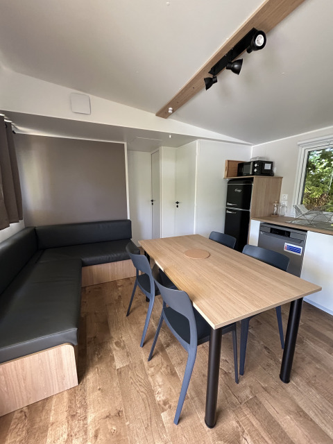 Indvendig udsigt over Prestige Cottage ved Camping Seasonova Les Marguerites i Frankrig, med spisebord.
