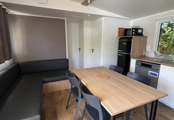 Indvendig udsigt over Prestige Cottage ved Camping Seasonova Les Marguerites i Frankrig, med spisebord.