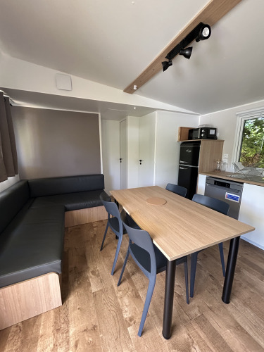 Vista interior del Prestige Cottage en Camping Seasonova Les Marguerites, Francia, con zona de comedor.