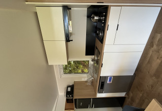 Moderne tekøkken i Prestige Cottage hos Camping Seasonova Les Marguerites i Frankrig med hvide skabe.
