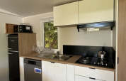 Pequeña cocina moderna en el Prestige Cottage de Camping Seasonova Les Marguerites, Francia, con muebles blancos.