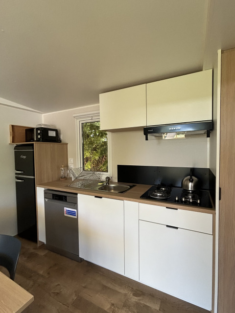 Pequeña cocina moderna en el Prestige Cottage de Camping Seasonova Les Marguerites, Francia, con muebles blancos.