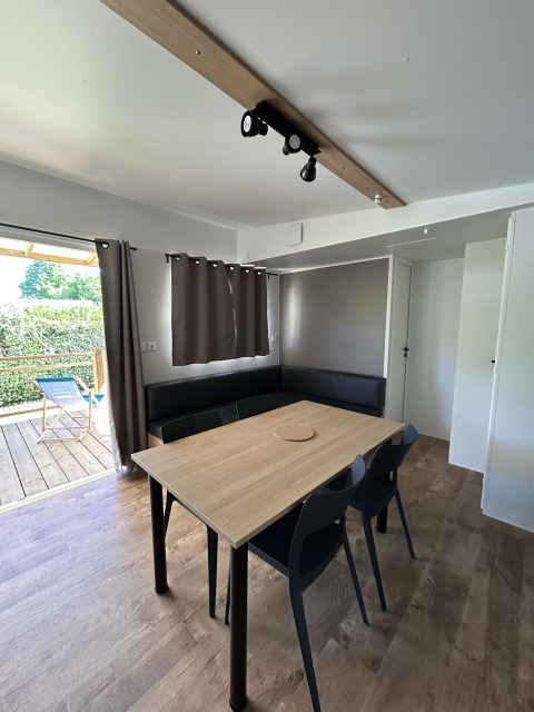 Vue intérieure du Prestige Cottage au Camping Seasonova Les Marguerites en France, avec table et chaises.