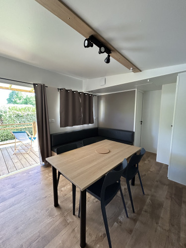 Vista interior del Prestige Cottage en Camping Seasonova Les Marguerites, Francia, con mesa y sillas.