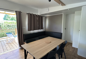 Innenaufnahme des Prestige Cottage im Camping Seasonova Les Marguerites in Frankreich mit Tisch und Stühlen.