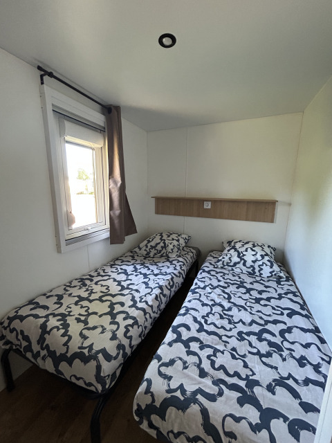Habitación con dos camas individuales y colchas modernas en Prestige Cottage, Camping Seasonova Les Marguerites, Francia.