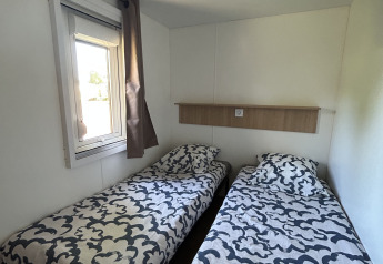 Camera con due letti singoli e copriletti moderni al Prestige Cottage, Camping Seasonova Les Marguerites, Francia.