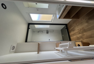 Baño moderno en Prestige Cottage, Camping Seasonova Les Marguerites, Francia, con ducha, lavabo y suelo de madera.