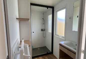 Bagno moderno nel Prestige Cottage al Camping Seasonova Les Marguerites, Francia, con doccia, lavandino e pavimento in legno.