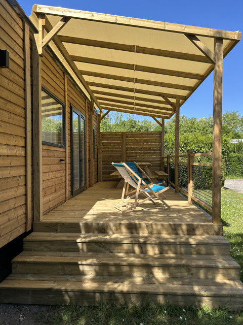 Prestige Cottage en Camping Seasonova Les Marguerites en Francia, con terraza de madera y tumbonas al sol.