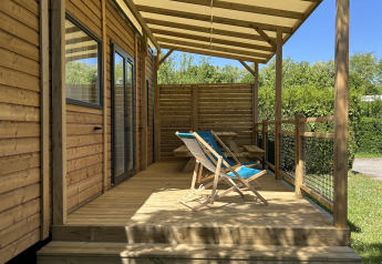 Prestige Cottage al Camping Seasonova Les Marguerites in Francia, terrazza in legno e sedie a sdraio al sole.