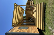 Cabaña de madera con terraza y sillas en Camping Seasonova Les Marguerites en Francia bajo cielo azul.