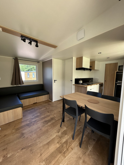 Vista interior de una cabaña moderna en Camping Seasonova Les Marguerites, Francia, con cocina y comedor.