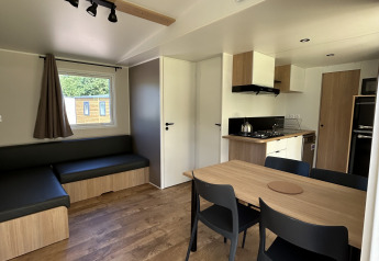 Indvendigt billede af en moderne hytte på Camping Seasonova Les Marguerites i Frankrig med køkken og spisebord.