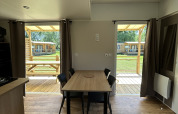 Innenansicht einer Hütte im Cottage bei Camping Seasonova Les Marguerites mit Tisch und Stühlen.